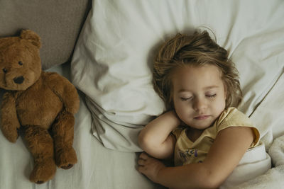 Portrait of cute little girl sleeping in bed with toy bear