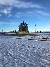 Statue on snow covered land against sky