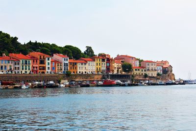 Houses by sea against clear sky