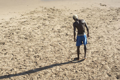 Rear view of shirtless man standing on beach