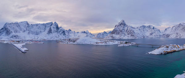 Scenic view of sea and snowcapped mountains against sky