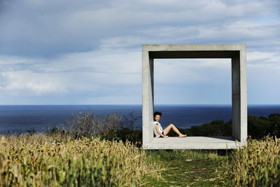 Girl sitting in concrete square and looking at sea