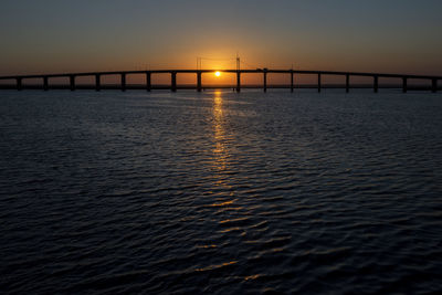 Bridge over sea against sky during sunset