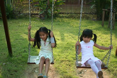 Friends swinging on swing at playground