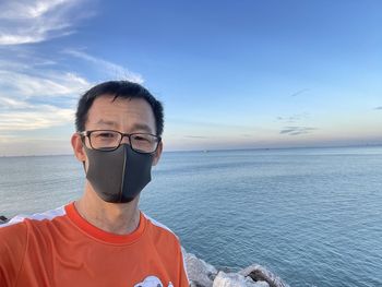 Low section of man standing by the sea