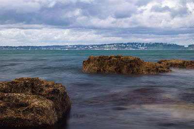 Rocks on sea shore against sky