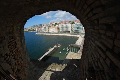 High angle view of buildings and sea seen through arch window