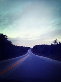 Empty road with trees in background