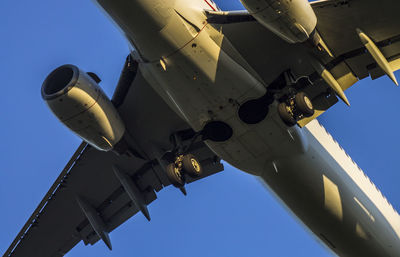 Low angle view of airplane against clear blue sky