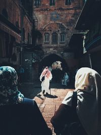 Rear view of people walking on table against building