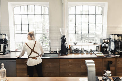 Rear view of woman standing by window