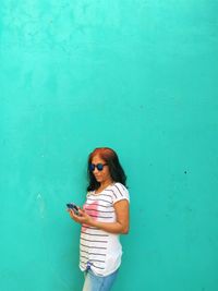 Young woman standing against blue wall