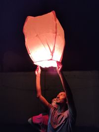 Midsection of man holding illuminated lantern at night