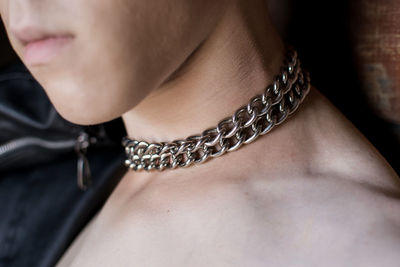 Mid section of topless mid adult woman wearing chain in neck