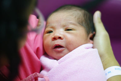 Close-up of cute baby girl held by mother