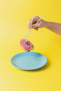 Midsection of person holding ice cream against yellow background