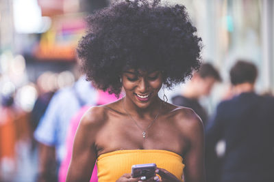 Happy young woman using smart phone on city street