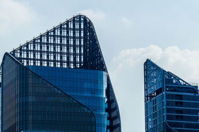 Low angle view of modern glass building against sky