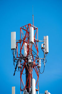 Low angle view of electricity pylon against clear blue sky