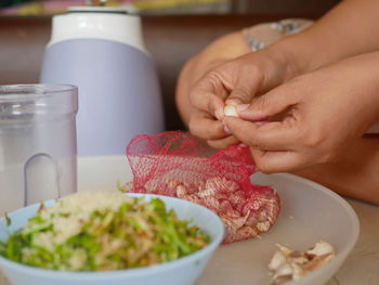 Woman's hands preparing, peeling fresh garlics to get them ready for blending with other ingredients