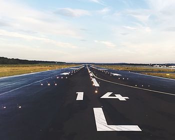 Illuminated lights on airport runway against sky