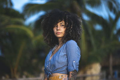 Curly haired woman looking away while standing at park