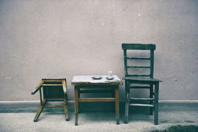 Empty chairs and table against wall