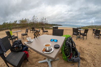 Chairs and table at beach against sky