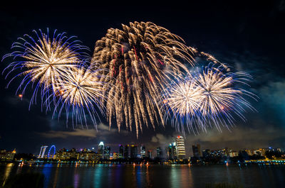 Low angle view of firework display over river at night