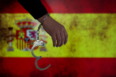 Cropped hand with handcuffs against spanish flag