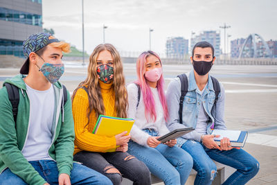 Friends wearing mask sitting outdoors