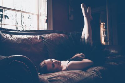 Female ballet dancer lying on sofa at home