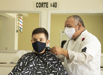 View of barber cutting hair of boy at barber shop