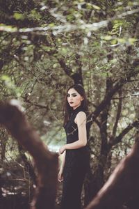 Young woman standing against trees in forest
