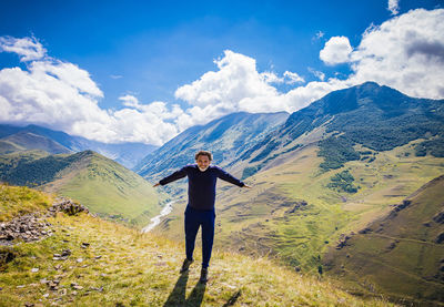 Rear view of man standing on mountain against sky