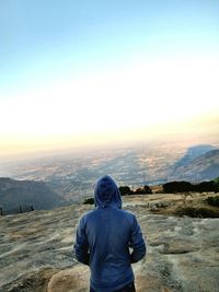 Rear view of man on rock against sky