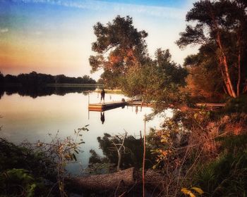 Scenic view of lake in forest during sunset