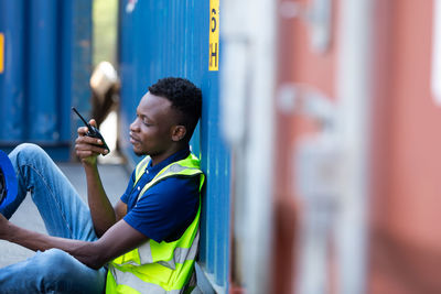 Side view of a young man talking on walkie-talkie at warehouse