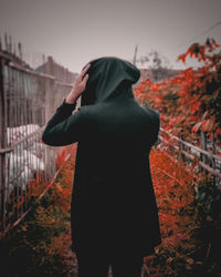 Rear view of man standing against sky during autumn