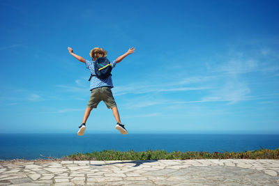 Full length of woman jumping on beach against sky