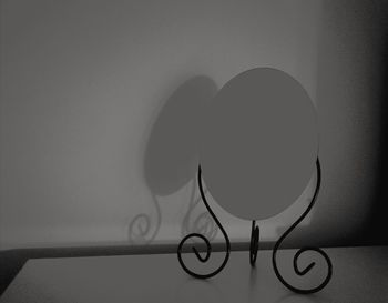 Close-up of electric lamp on table against wall at home
