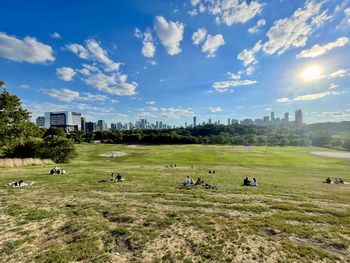 People walking on grassy field against sky