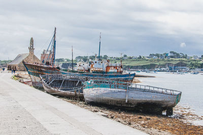 Boats moored at harbor against sky