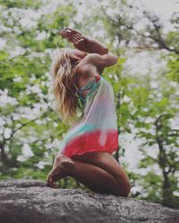 Low angle view of woman practicing yoga on tree trunk in forest