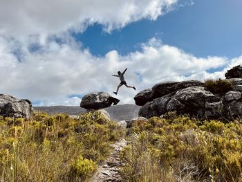 Low angle view of man standing on rock against sky