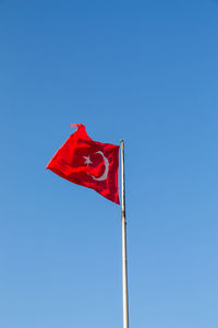 Low angle view of flag against clear blue sky