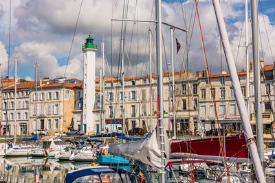 Sailboats moored in harbor against buildings in city