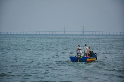 People on boat in sea against clear sky