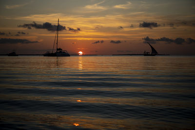 Silhouette sailboat in sea against sky during sunset