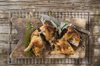 Directly above shot of roast chicken on cutting board with rack over wooden table